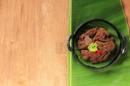 Rendang o Randang es la comida más deliciosa del mundo. Elaborado con guiso de abejas y leche de coco con varias hierbas y especias. Comida típica de la tribu Minang, Sumatera Occidental, Indonesia. Copiar espacio sobre fondo de madera