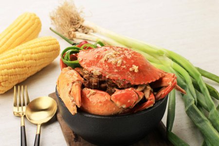 Photo for Chilli Mud Crab, Crab with Singaporean Sauce, Special Singapore Cuisine. Served on Black Bowl with Gold Spoon and Fork - Royalty Free Image