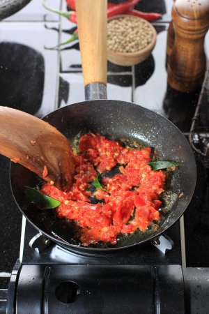 Foto de Cooking Process Saute Sambal or Sambel or Spicy Sauce on a Pan in the Kitchen using Wooden Spatula. Messy Kitchen during Cooking Backstage - Imagen libre de derechos