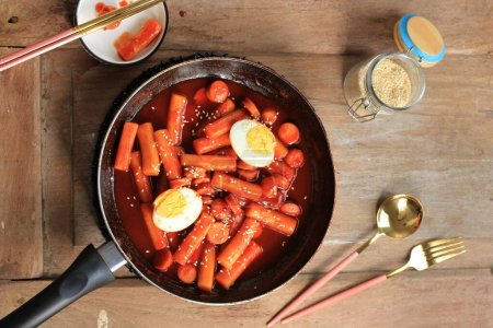 Enfoque selectivo Topokki o Tteokbokki es pastel de arroz frito con verduras y pastel de pescado en salsa picante Top con semillas de sésamo, comida callejera coreana famosa y popular
