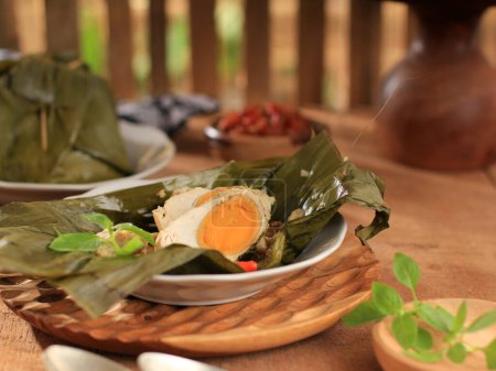 Photo for Pepes Telur Asin is an Indonesian Food Made from Salted Egg Mixture of Spices, Basil Leaves, and Coconut Milk. Wrapped with Banana Leaf and Steamed. - Royalty Free Image