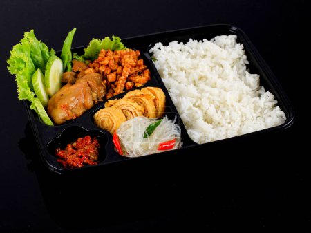 Téléchargez les photos : Boîte de riz ou Nasi Kotak indonésien avec sauce soja poulet, tempeh Oreg et pâte épicée, sur table blanche - en image libre de droit