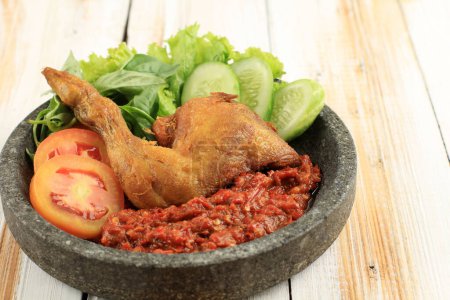 Photo for Ayam Penyet or Penyetan Ayam, Fried Chicken Served with Spicy Sambal on Wooden Table - Royalty Free Image