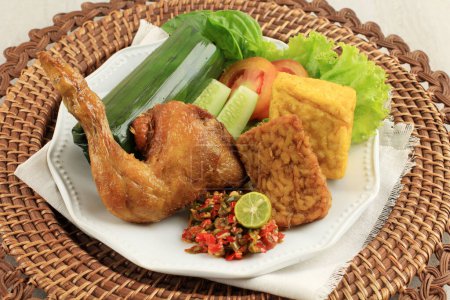 Photo for Nasi Timbel Komplit, Traditional Sundanese Rice Wrapped with Banana Leaf, Served with Fried Chicken, Tempeh, Tofu, and Chilli Paste - Royalty Free Image