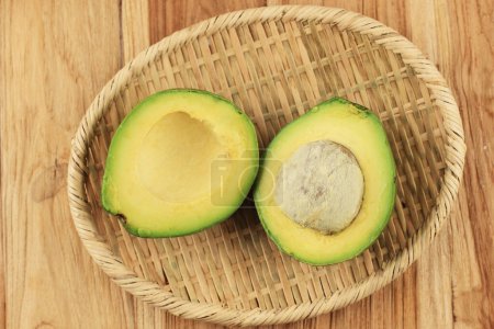 Photo for Slice Avocado on Rattan Plate, Above Wooden Table - Royalty Free Image
