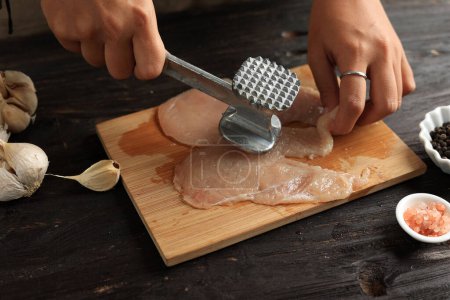 Cooking Breast Chicken Meat, Female Hand Beat Chicken using Meat Tenderizer. Cooking Process in The Kitchen. 