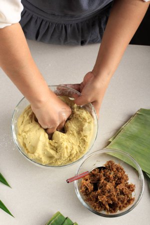 Téléchargez les photos : Top View Pâte à pétrir faisant une collation traditionnelle asiatique avec du sucre de palme enveloppé avec feuille de banane - en image libre de droit