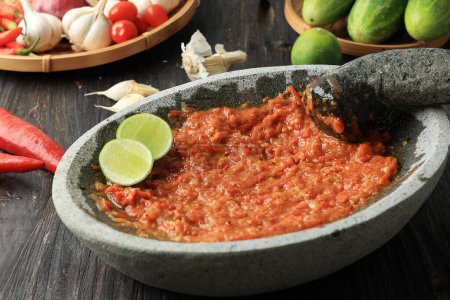 Foto de Sambal Tomat or Spicy Tomato paste on Stone Mortar and Pestle, Indonesian Traditional Grinder. Fresco hecho. - Imagen libre de derechos