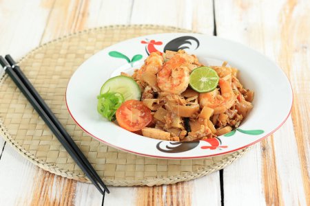 Photo for Seafood Kwetiau Goreng with Egg, Shrimps, Fish Meatball, and Lime. Stir Fry Char Kway Teow with Prawn On White Table - Royalty Free Image