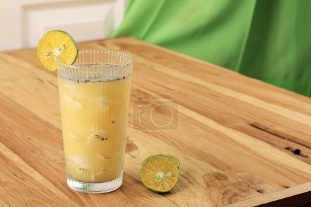 Photo for Es Kelapa Jeruk or Young Coconut with Squeezed Orange, Indonesian Tropical Refreshment Drink during Summer. On Wooden Table - Royalty Free Image