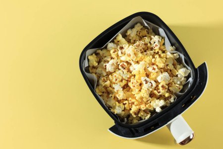 Photo for Top View Air Fryer Tray with Butter Popcorn on Yellow Table Background, Copy Space for Text - Royalty Free Image