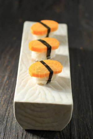 Foto de Sushi de tres huevos de Tamago Nigiri con Nori en mesa de madera, arroz con huevos enrollados con cinturón de Nori - Imagen libre de derechos