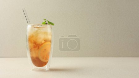 Foto de Té de limón helado o Es Teh en fondo crema con paja de vidrio - Imagen libre de derechos