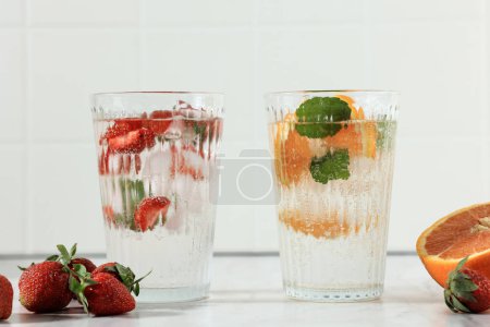 Strawberry and Orange Soda with Mint Leaf and Ice Cube on White Table 