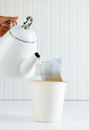 Gießen Sie heißes Wasser essen Instant Cup Nudel, auf weißem Tisch 