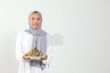 Indonesische Frauen halten weißen Teller mit Ketupat, Reiskuchen mit Diamantform für Eid Al Fitr oder Lebaran Hari Raya Festfeier