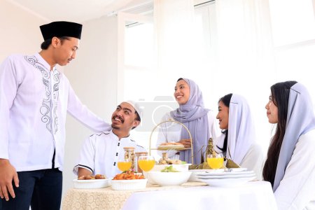 Téléchargez les photos : Famille ou amis asiatiques excités célèbrent Hari Raya Idul Fitri Eid al Fitr, Parler et manger ensemble - en image libre de droit