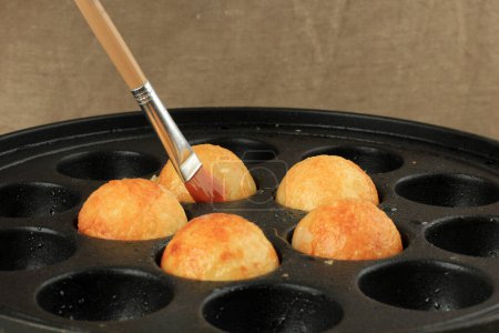 Cepillado de la sartén Takoyaki con aceite, proceso de cocción haciendo bolas Takoyaki 