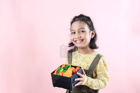 Little Female Asian Kids Showing Her Healthy Lunchbox with Happy Face on Pink Background