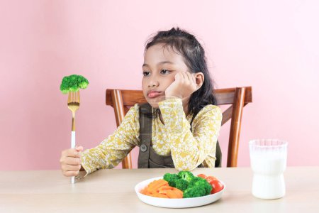 Asian Little Cute Girl se niega a comer brócoli verduras saludables. Picky Eater Concepto para niños