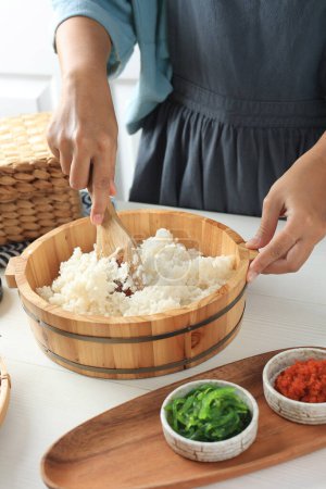 Female Asian Hold Bamboo Rice Spoon making Chirashizushi, Japanese Rice Concept on Hangiri 