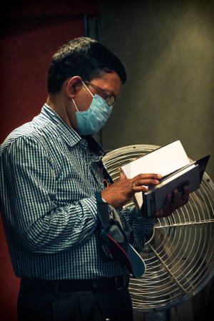 Foto de Kolkata, India - 12 de febrero de 2023: Un retrato lateral de un hombre absorto en la lectura de un libro en la Feria del Libro de Kolkata. Enfoque selectivo. - Imagen libre de derechos