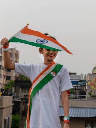 Foto de Linda niña india ondeando bandera india celebrando el Día de la Independencia india mostrando patriotismo. Enfoque selectivo en la bandera - Imagen libre de derechos
