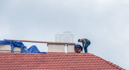Photo for Nitra, Slovakia - 05.15.2023: Handymen repair chimneys on the roof of a house. - Royalty Free Image