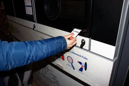 Foto de Nitra, Eslovaquia - 01.16.2024: Primer plano de la mano de un hombre que recibe un cheque por los contenedores devueltos. - Imagen libre de derechos