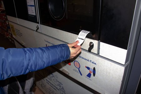 Foto de Nitra, Eslovaquia - 01.16.2024: Primer plano de la mano de un hombre que recibe un cheque por los contenedores devueltos. - Imagen libre de derechos