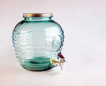 Large glass container for wine with a tap on a white background.