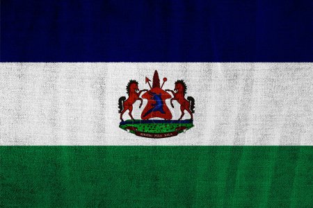 Flagge und Wappen des Königreichs Lesotho auf strukturiertem Hintergrund. Konzeptcollage.