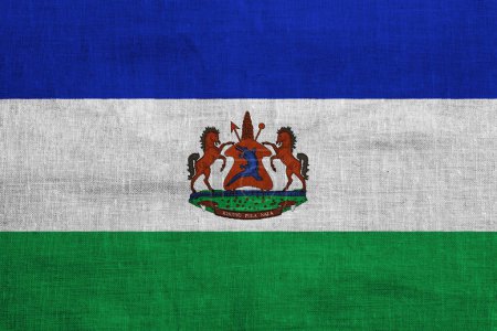 Flagge und Wappen des Königreichs Lesotho auf strukturiertem Hintergrund. Konzeptcollage.