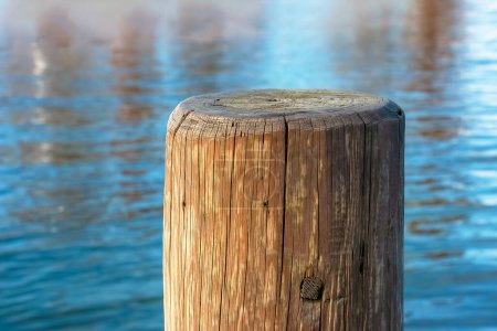 Ein Steg aus Holzpfählen zum Anlegen von Booten und zur Aufrechterhaltung der Stabilität der Seebrücke vor der Kulisse des Traunsees in Österreich.