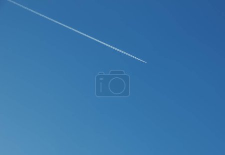 Airplane condensation trail and airplane on blue sky