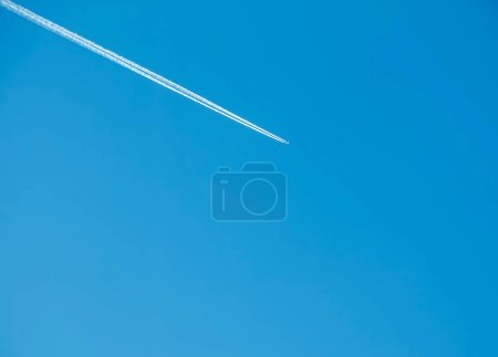 Airplane condensation trail and airplane on blue sky