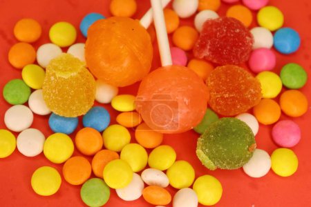 Köstliche Süßigkeiten und Edelsteine auf dem roten Hintergrund