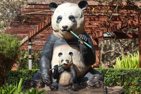 Madre bebé panda comiendo estatua en el zoológico indio