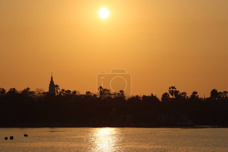 Eine Spiegelung des Sonnenuntergangs auf dem Fluss mit orangefarbenem Himmel