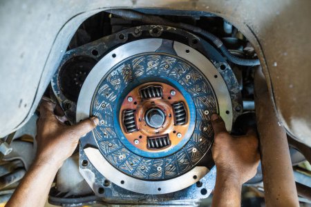 Mechanic's hand installing new clutch plate in car, clutch system, auto mechanic in garage,service clutch system.