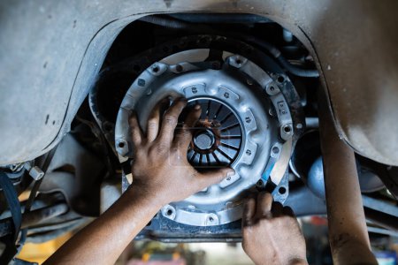 Auto mechanic working in auto repair shop. Hands of mechanic repairing car.Installing new clutch plate in car, clutch system, auto mechanic in garage,service clutch system.
