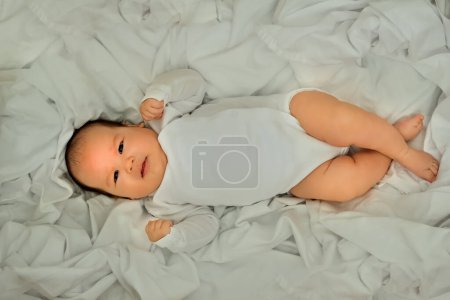 Photo for Newborn baby smiles and laughs. shows emotions. baby lies on a white cloth - Royalty Free Image