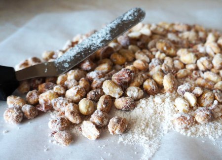 Téléchargez les photos : Arachides rôties dans du sucre glace. Arachide en sucre en poudre avec une pelle métallique. arachide, goober, singe, arachide - en image libre de droit