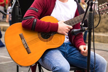 Téléchargez les photos : Guitare acoustique. L'homme tient une guitare en main. Le chanteur avec une guitare. Acteur de rue - en image libre de droit