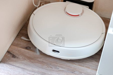 Photo for White robot vacuum cleaner. robotic exhauster is charging energy. top view. Apartment Cleaning Assistant Robot Concept - Royalty Free Image