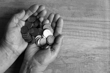 Coins in the palms. Money in hand. Poverty concept, cash shortage.Saving.  On a coin it is written in Ukrainian - 50, 25 and 5 kopecks. black and white photo