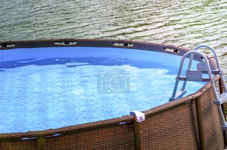 The  Frame pool with blue water outdoor. Near the river the Frame pool. The blue area on which the inflatable basin. Water in the reservoir against the background of water in the river. frame swimming pool