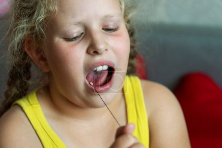 girl holds thread to pull out a milk tooth.  Removal of tooth at the child. The concept loss of milk teeth at children. Dental care to children.Toothache concept, dental problems