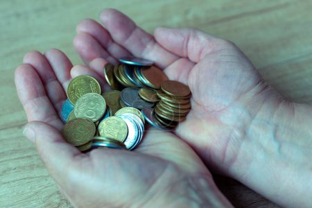 Monedas en las palmas. Dinero en mano. Concepto de pobreza, escasez de efectivo. Ahorro. En la moneda es escrito en ucraniano - 50, 25 y 5 kopecks.