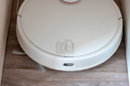 Photo for White robot vacuum cleaner. robotic exhauster is charging energy. top view. Apartment Cleaning Assistant Robot Concept - Royalty Free Image